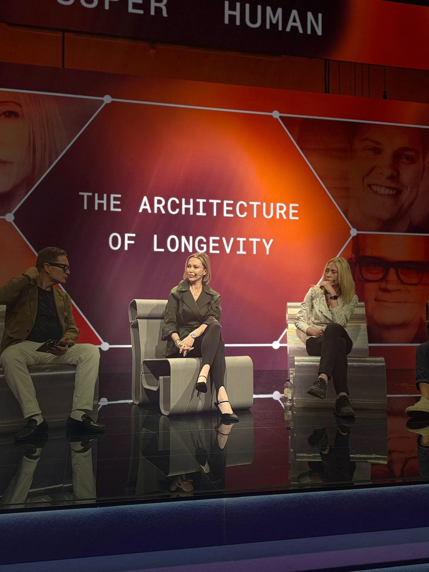 Kas Bordier on stage at Super Human in Stockholm, beneath a screen reading The Architecture of Longevity