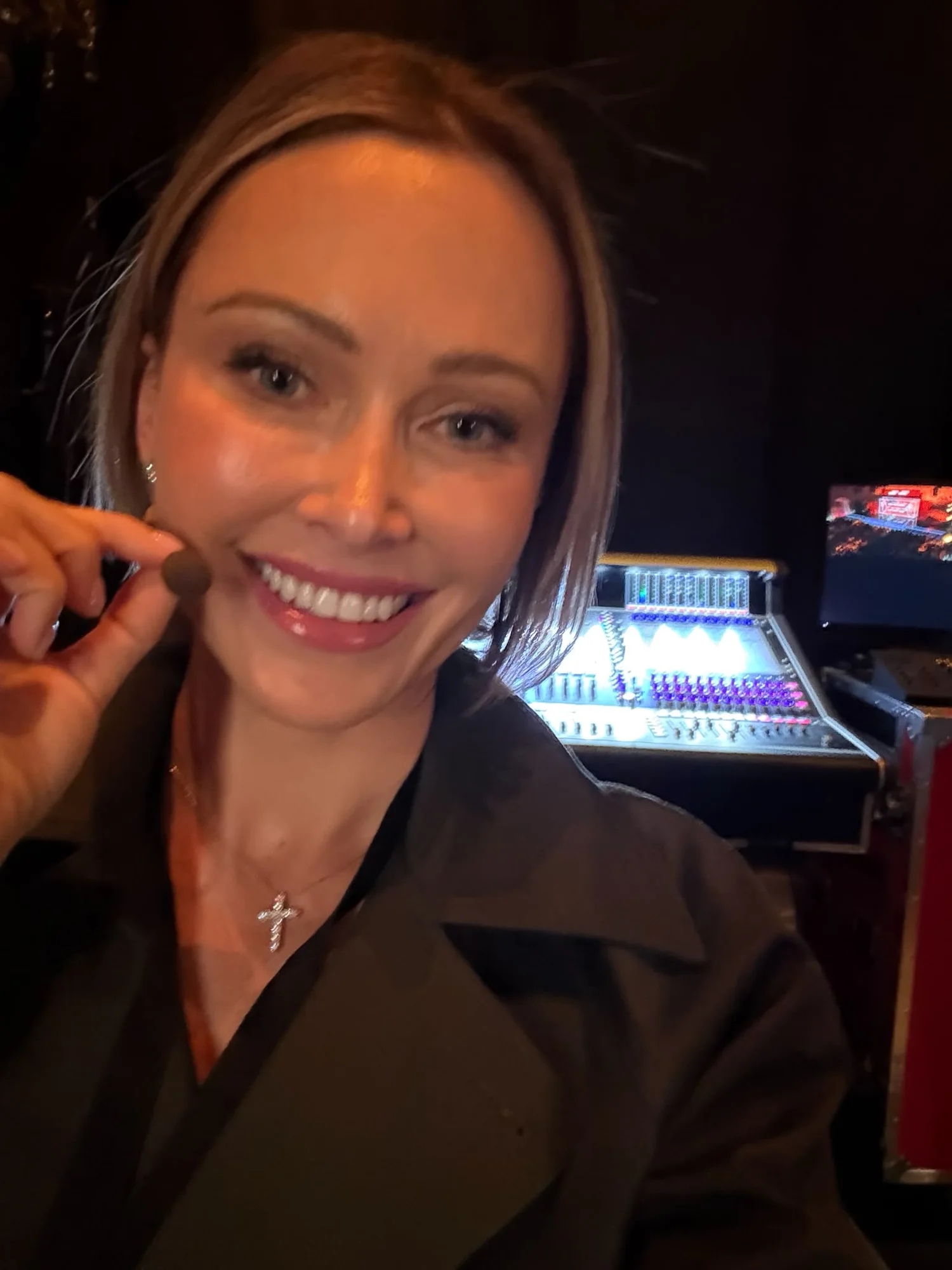 Kas Bordier backstage before the panel, holding her stage microphone, the lighting desk behind her