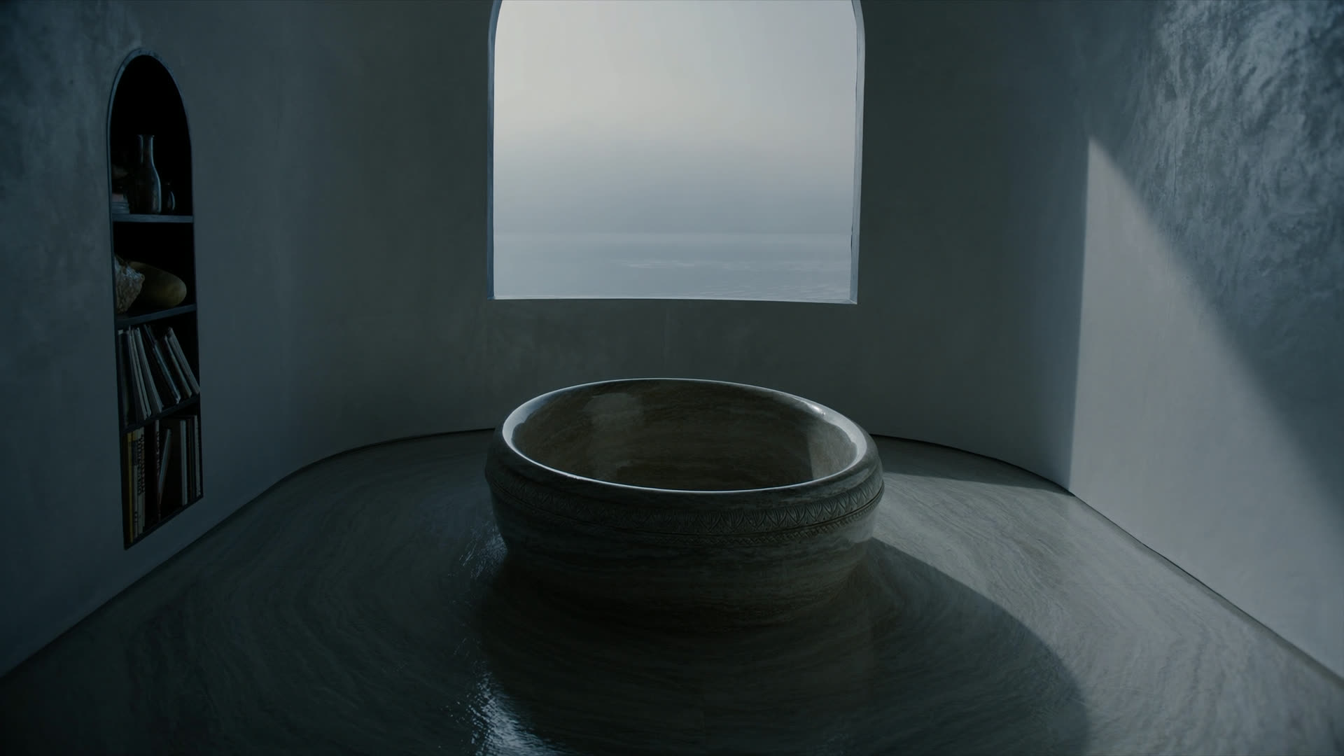 A carved travertine soaking tub on a curved plaster floor, lake fog beyond