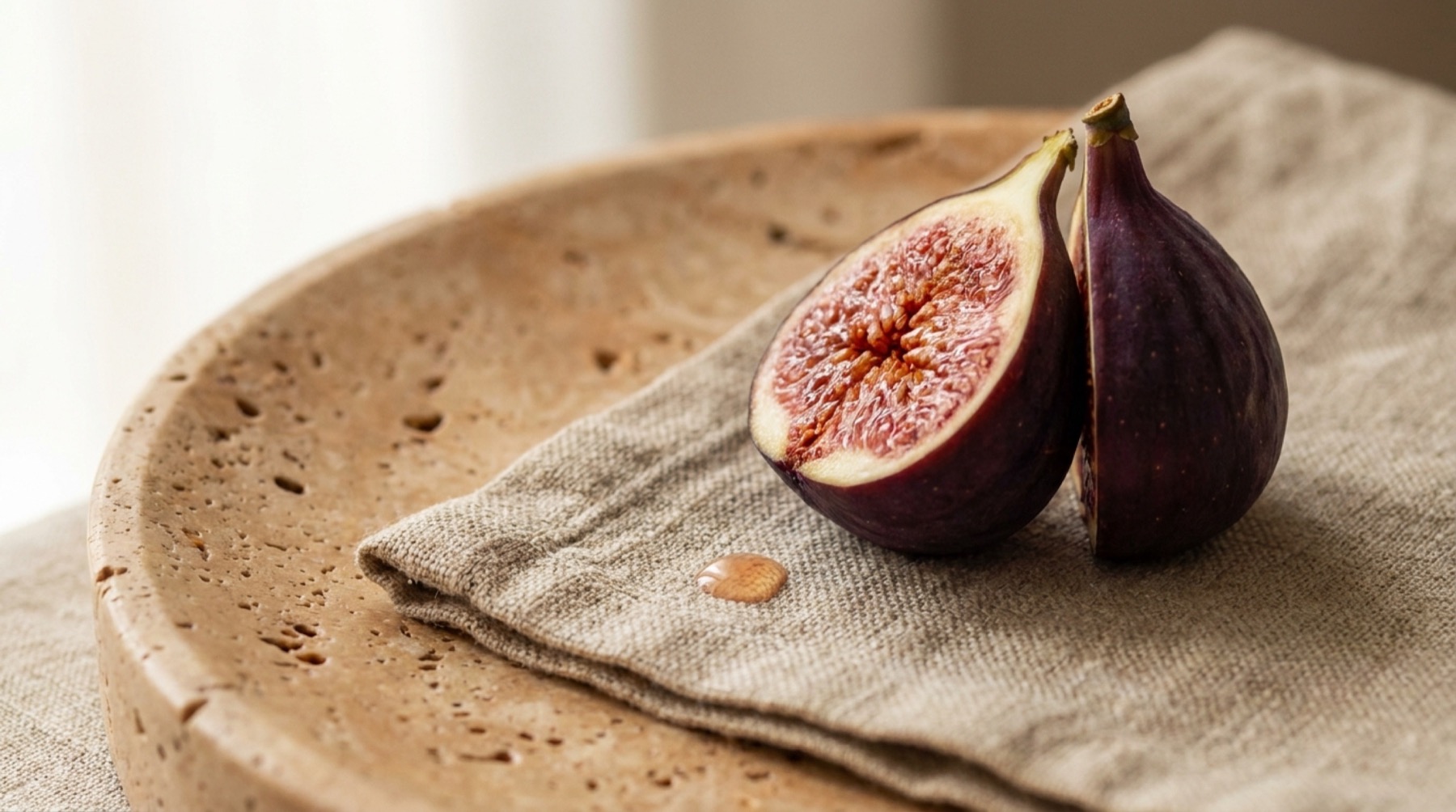 A halved fig on a linen cloth on a travertine plate